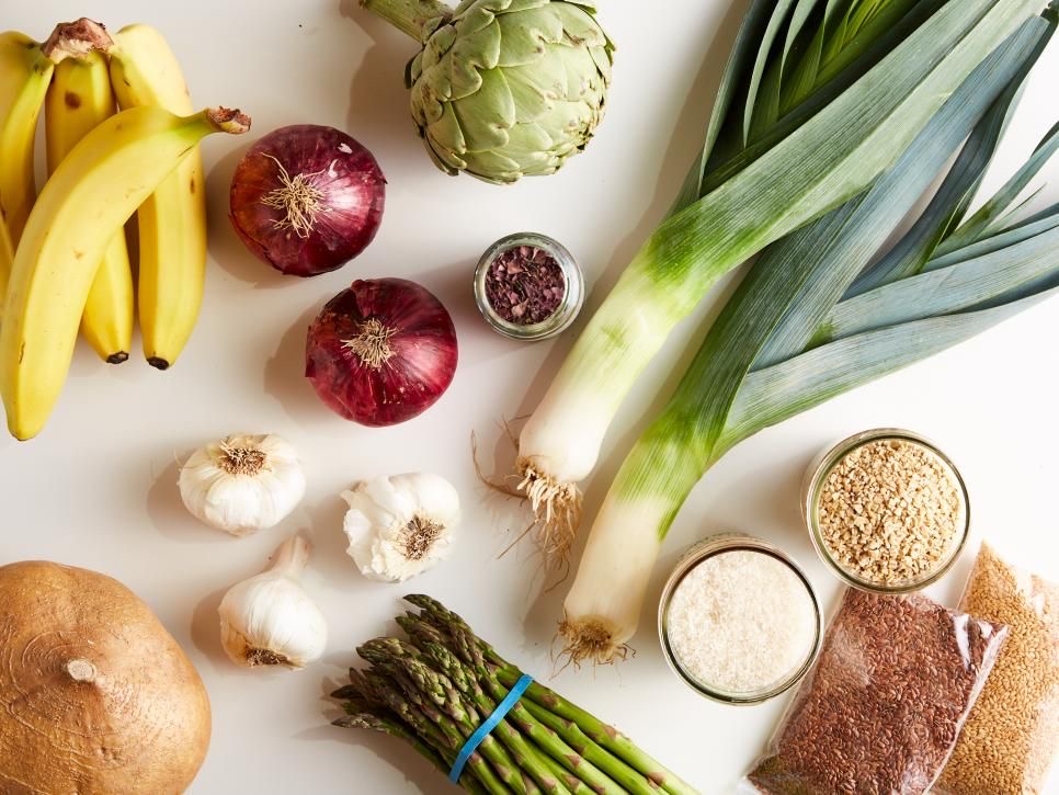 Variedad de alimentos ricos en probióticos y prebióticos sobre fondo blanco