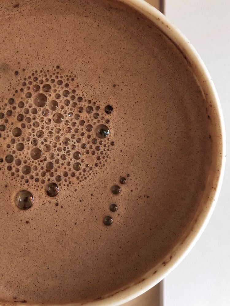 Taza de chocolate caliente con cacao ceremonial, espuma cremosa y burbujas en la superficie